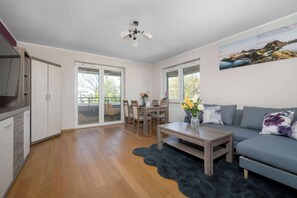 A modern living room with a sofa, coffee table, and dining area. - Family Apartment in Wroclaw | Balcony | Parking | 2 Bedrooms (Wrocław)