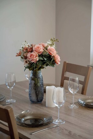 A dining table with a vase of flowers, candles, and wine glasses. - Family Apartment in Wroclaw | Balcony | Parking | 2 Bedrooms (Wrocław)