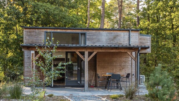 Eine moderne Holzdiele mit überdachter Terrasse, Essbereich und Kiesweg.