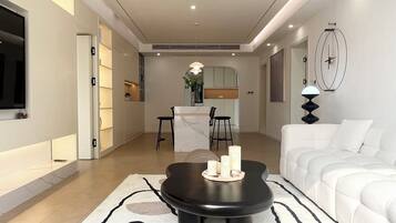 A modern living room with a sofa, a coffee table, and a dining area in the background.