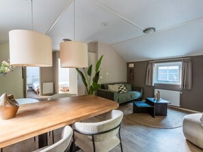 A modern living room with a wooden dining table, two chairs, a sofa, and a coffee table. - Vakantiepark De Wiltzangh - Veenborg Lodge by Interhome (Ruinen)