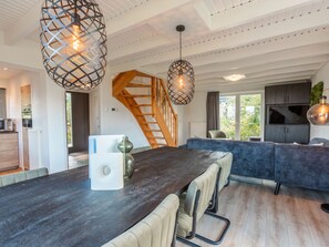 A modern kitchen with a built-in oven, a dining area with a dark wooden table and cushioned chairs, and a staircase leading to an upper level. - Vakantiepark Wiedense meren - Weerribben by Interhome (Wanneperveen)