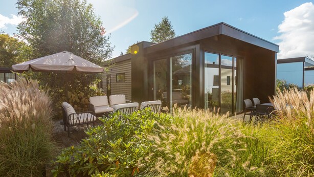 Een modern huis met terras, zitplaatsen buiten en uitzicht op de lucht.