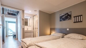 Ett hotellrum med en säng, ett nattduksbord, en spegel och ett badrum med dusch.