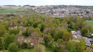 Ett flygbildsbild av ett bostadsområde med hus, grönområden och en väg.
