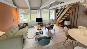 Un grand espace de vie comprenant un canapé, une table à manger, un téléviseur et un escalier.