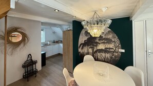 Un espace repas agrémenté d’un lustre, d’une table ronde et d’une fresque murale.