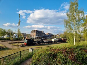 Ein Bahnhof mit einem stehenden Zug, Gleisen und einem Gebäude im Hintergrund.