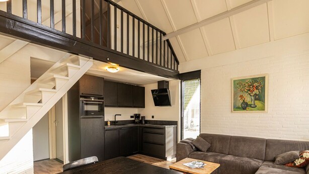Un ambiente abitativo in stile loft con una scala, cucina e zona salotto.
