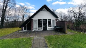 Une maison de plain-pied avec un toit en pente, un porche à l’avant et un patio.