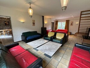 Ein großzügiger Wohnbereich mit Kamin, Ledersofas und einem Essbereich mit Holztisch und -stühlen.