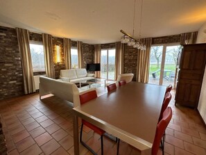 Ein geräumiger Essbereich mit einem großen Tisch, Stühlen, einer Couch und einem Fernseher.