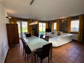 Ein Essbereich mit Tisch und Stühlen, ein weißes Sofa und ein Kamin.