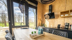 A modern kitchen with a large island, a built-in stove, and a view of the outdoors. - Vakantiepark Aan de Maas - Weide Lande 4 personen by Interhome (Kerkdriel)