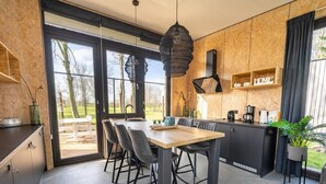 A modern kitchen with a dining area, large windows, and a view of the outdoors. - Vakantiepark Aan de Maas - Weide Lande 4 personen by Interhome (Kerkdriel)