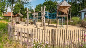 Un parque infantil con estructuras de madera, puentes colgantes y una zona delimitada.