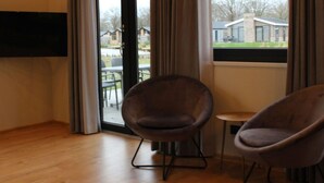 A room with a large window, a wooden floor, and two armchairs. - Vakantiepark Aan de Maas - Weide Lande 6 personen by Interhome (Kerkdriel)