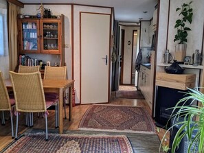 Ein Essbereich mit Holztisch und Stühlen, einer Vitrine und einer Küchenzeile mit Herd und Schränken.