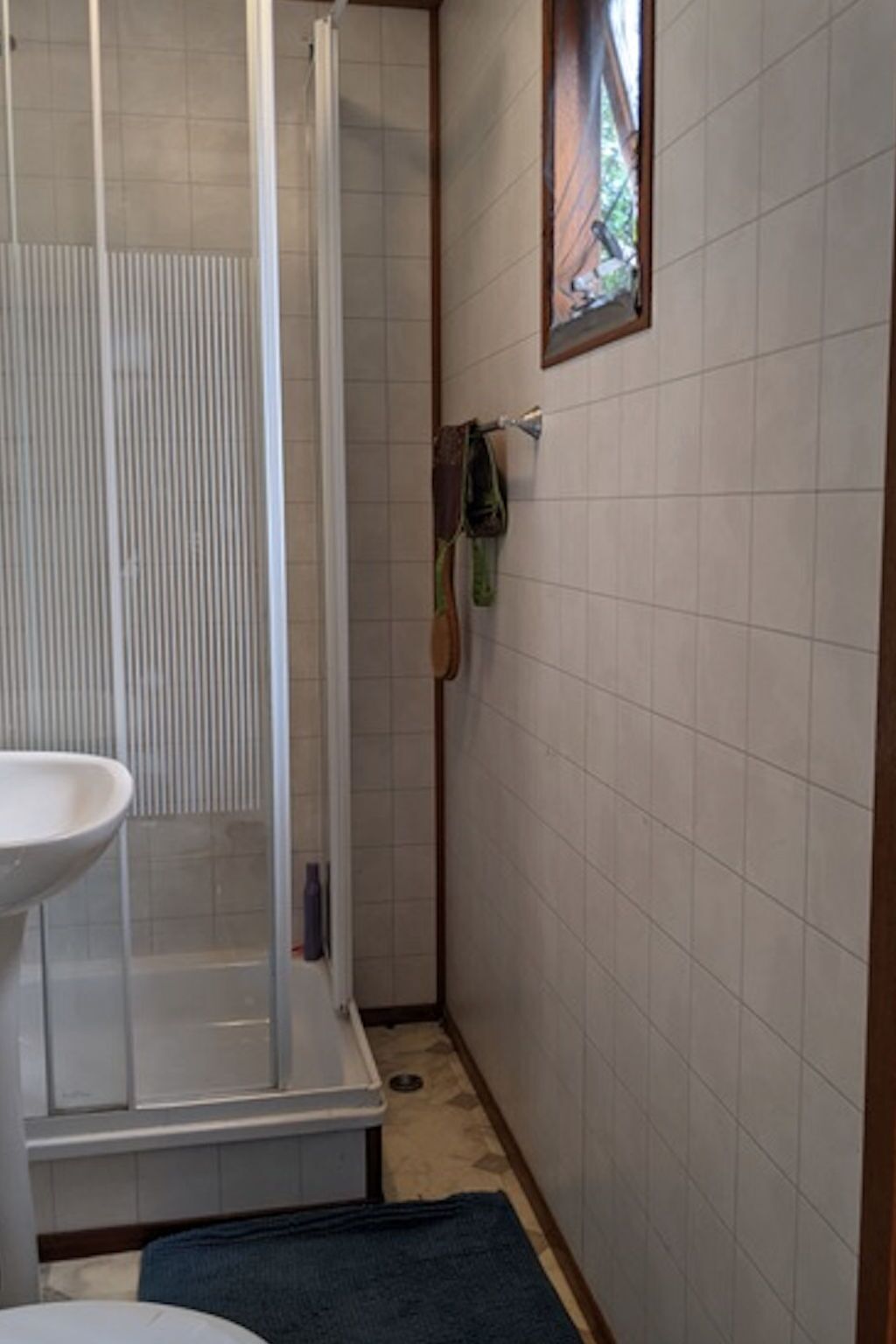 A bathroom with a shower, a sink, and a towel rack.