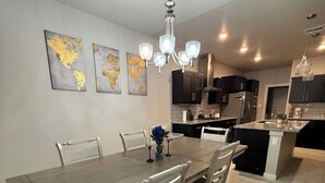 A modern kitchen with dark cabinets, a central island, and a dining area with a wooden table and chairs.