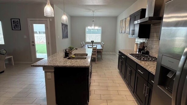 A modern kitchen with granite countertops, stainless steel appliances, and pendant lighting.