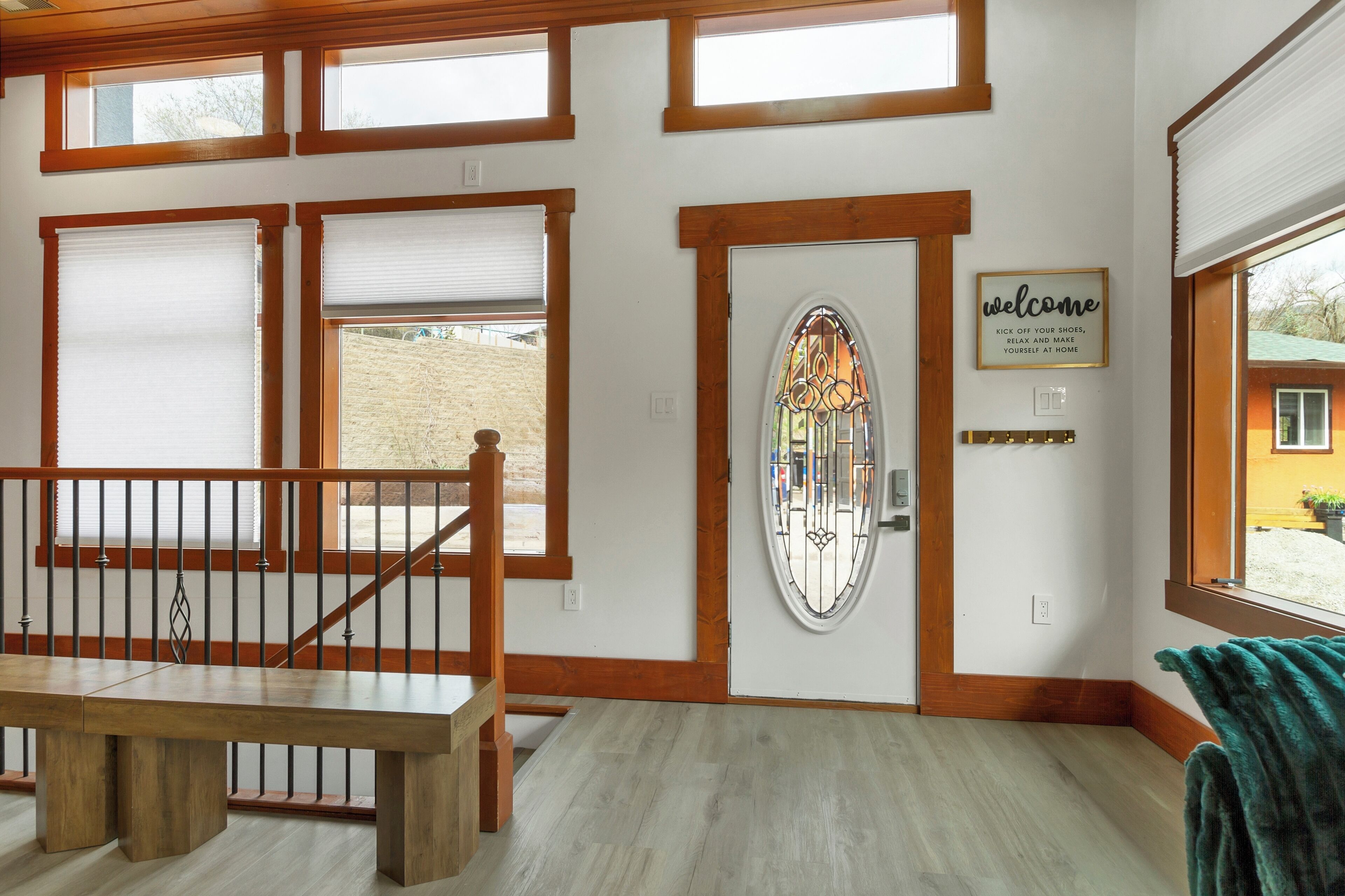 Una habitación con un banco de madera, una puerta con un vitral y un letrero de bienvenida.