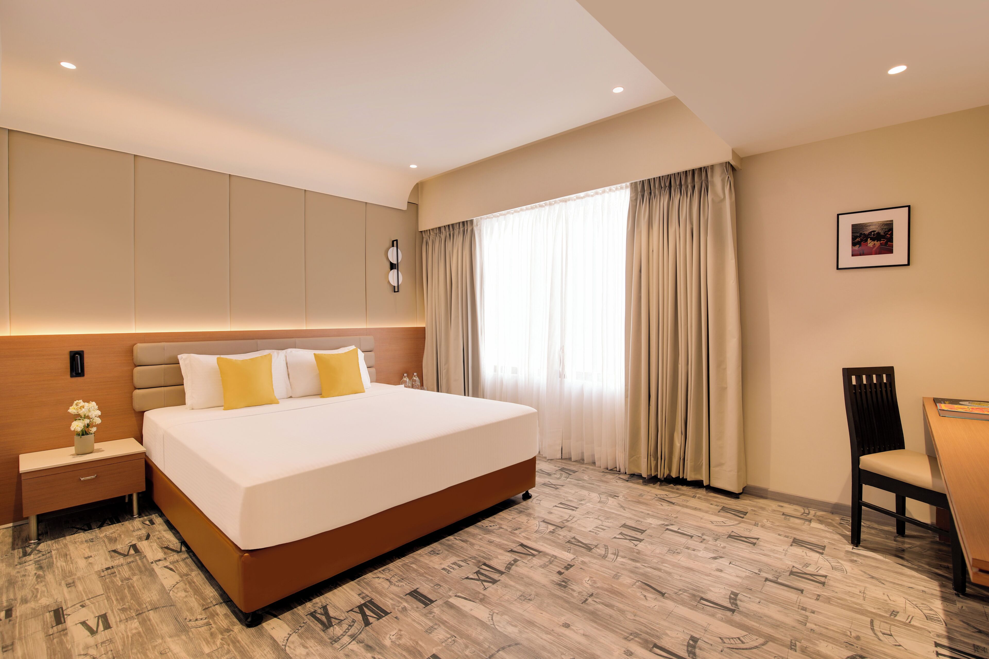 Una habitación de hotel con una cama grande, una mesita de noche, una silla y un escritorio.