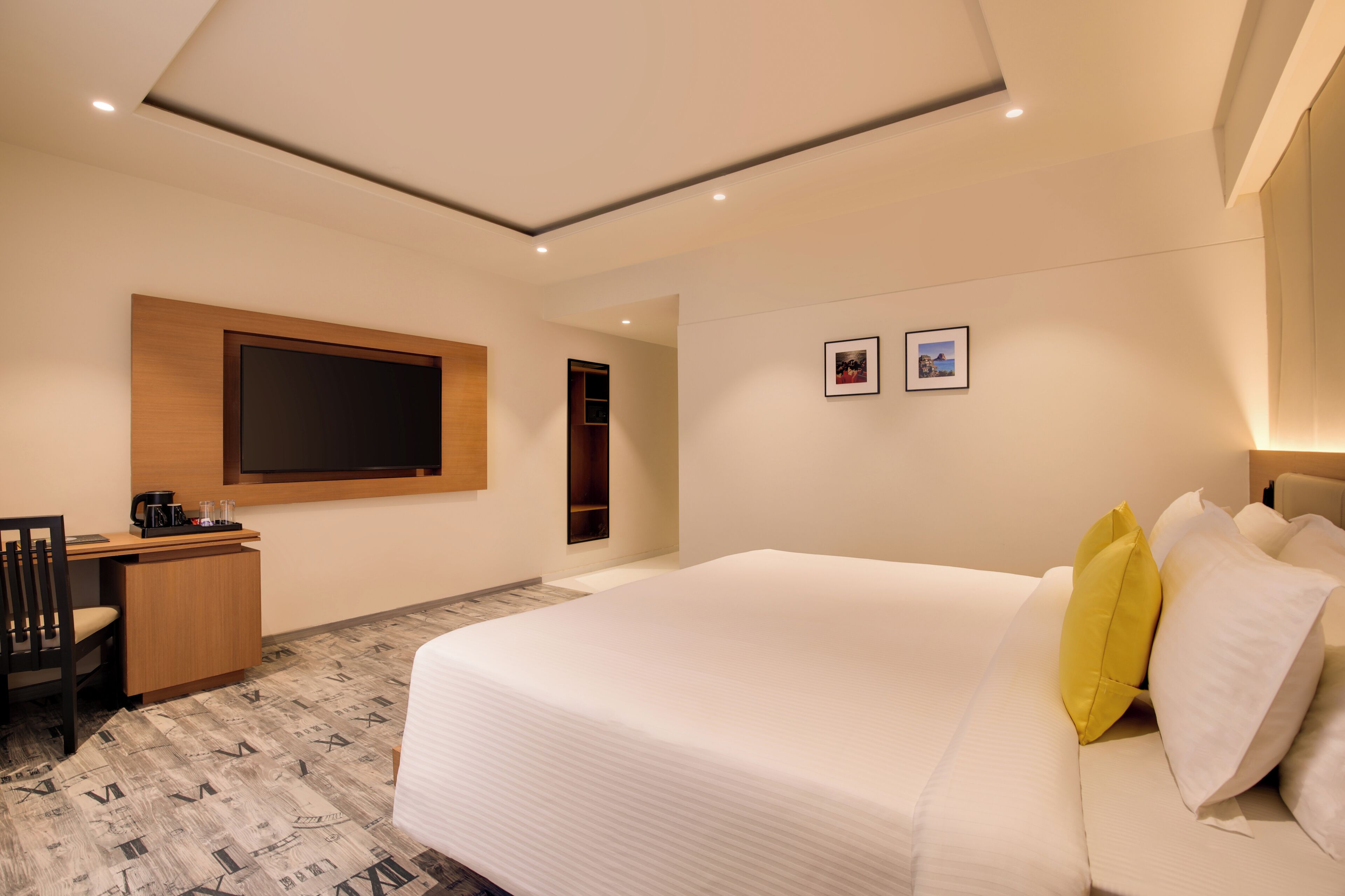 Une chambre d’hôtel équipée d’un lit, d’un bureau, d’une chaise et d’un téléviseur fixé au mur.