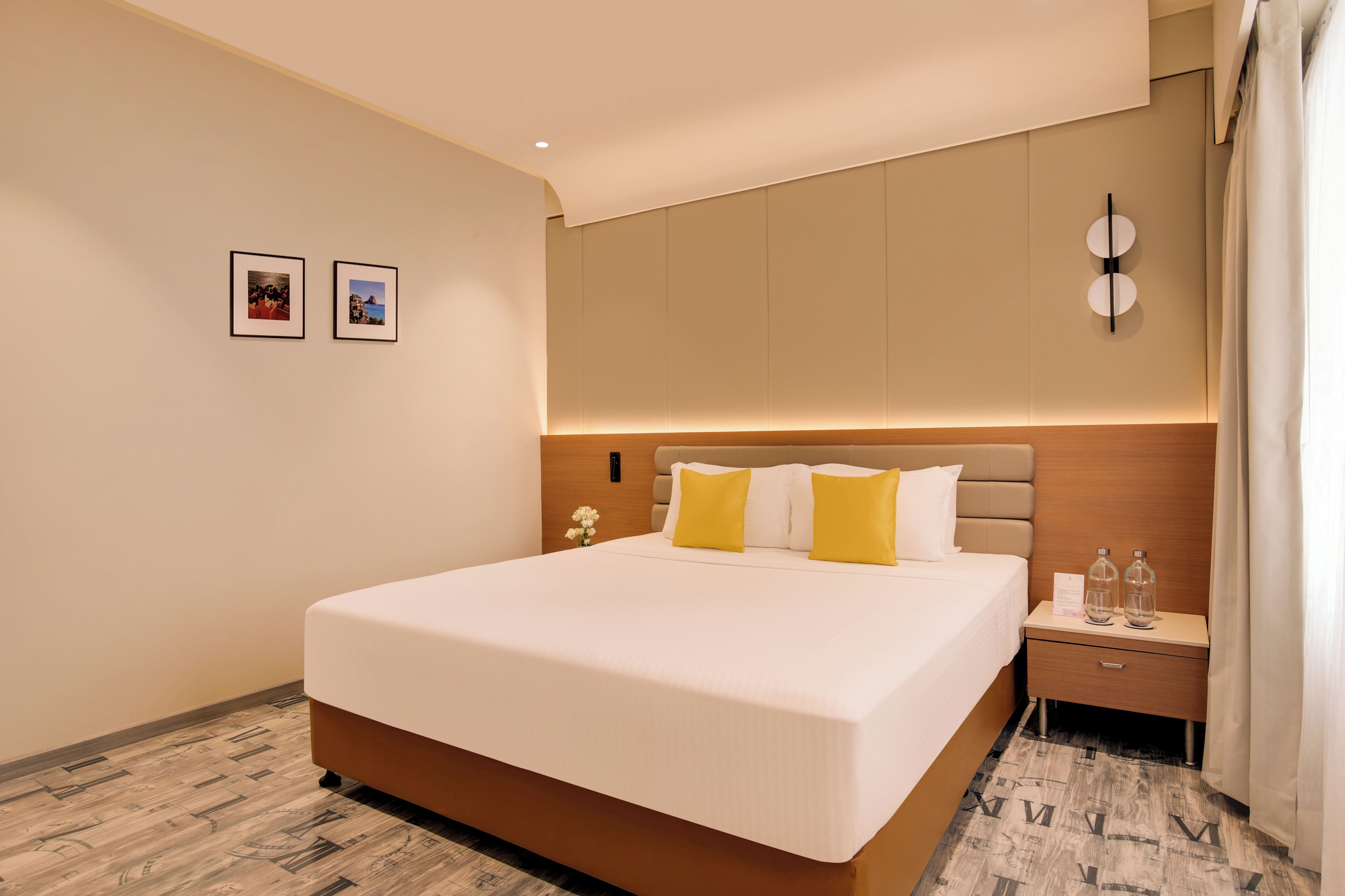 A modern hotel room with a large bed, a nightstand, and a wall-mounted clock.