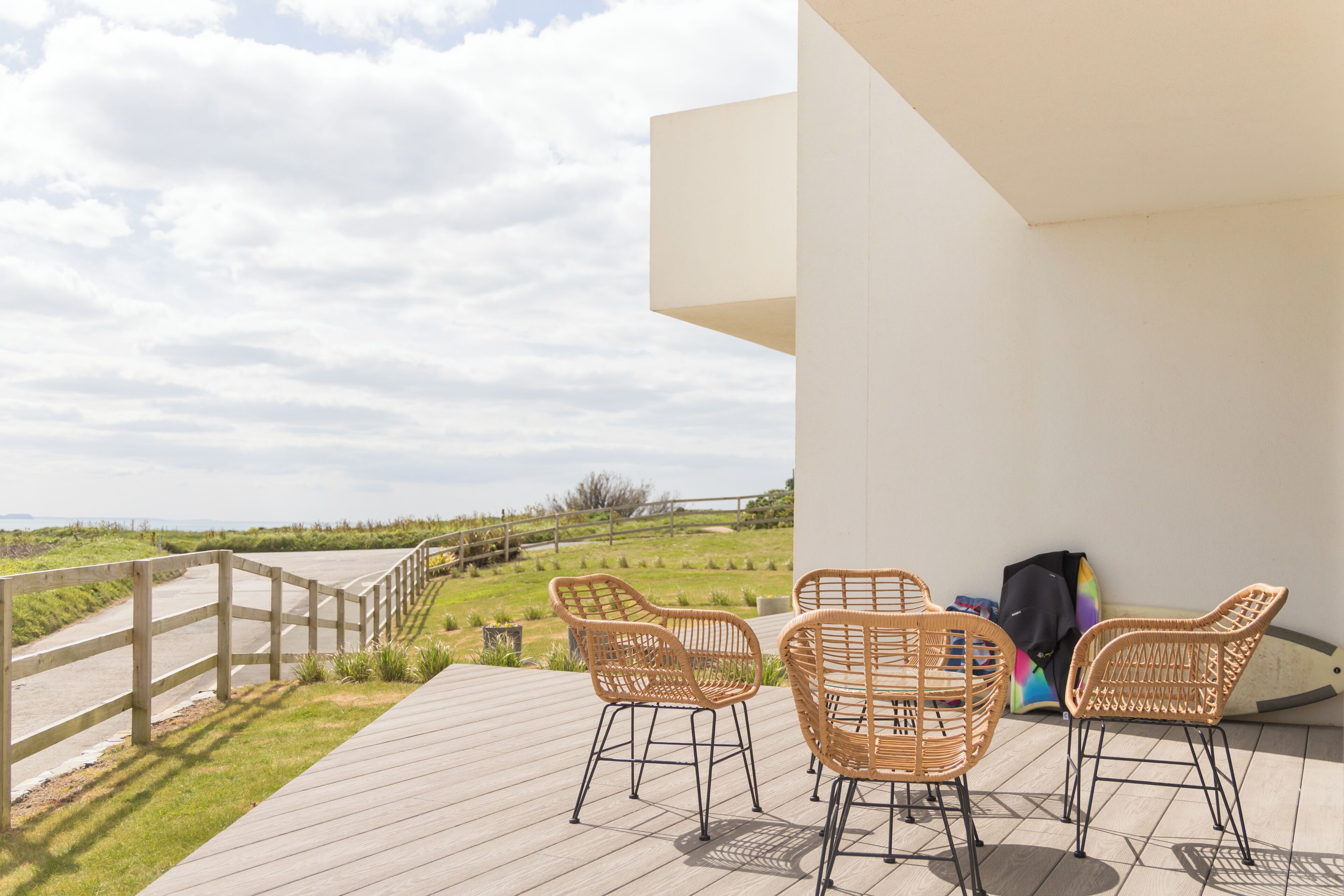 A wooden deck with wicker chairs and a view of the beach.