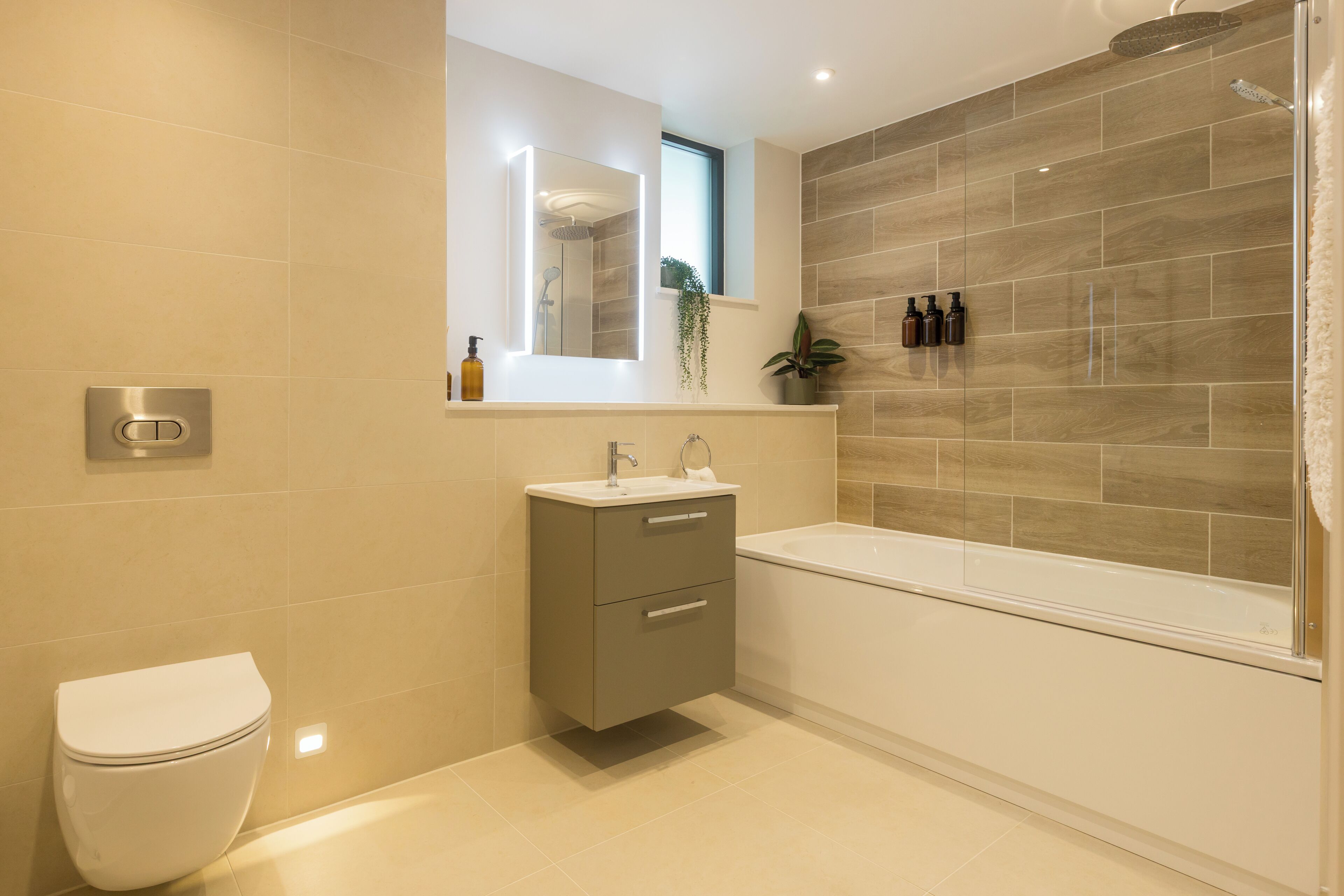 A modern bathroom with a toilet, sink, vanity, and a bathtub.