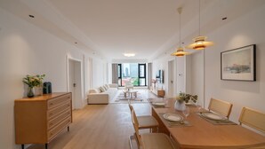 Een moderne eetruimte met een lange tafel, stoelen en hanglampen.
