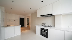 Een moderne keuken met witte kasten, een inbouwoven en een gasfornuis.