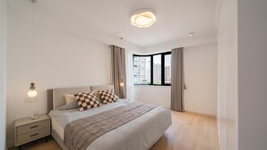 Een moderne slaapkamer met een bed, nachtkastje en een raam met uitzicht op de stad.