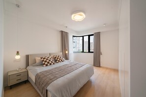 Ein modernes Schlafzimmer mit Bett, Nachttisch und Fenster mit Blick auf die Stadt.