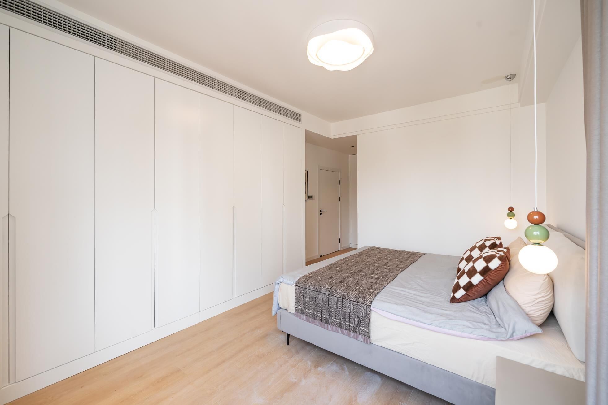 A bedroom with a bed, a wardrobe, a door, and a ceiling light.