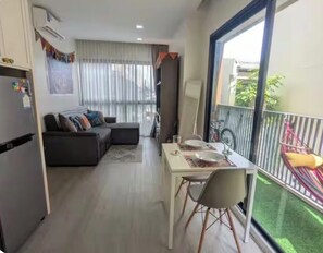 Un espacio habitable compacto con comedor, sofá y balcón con una bicicleta.
