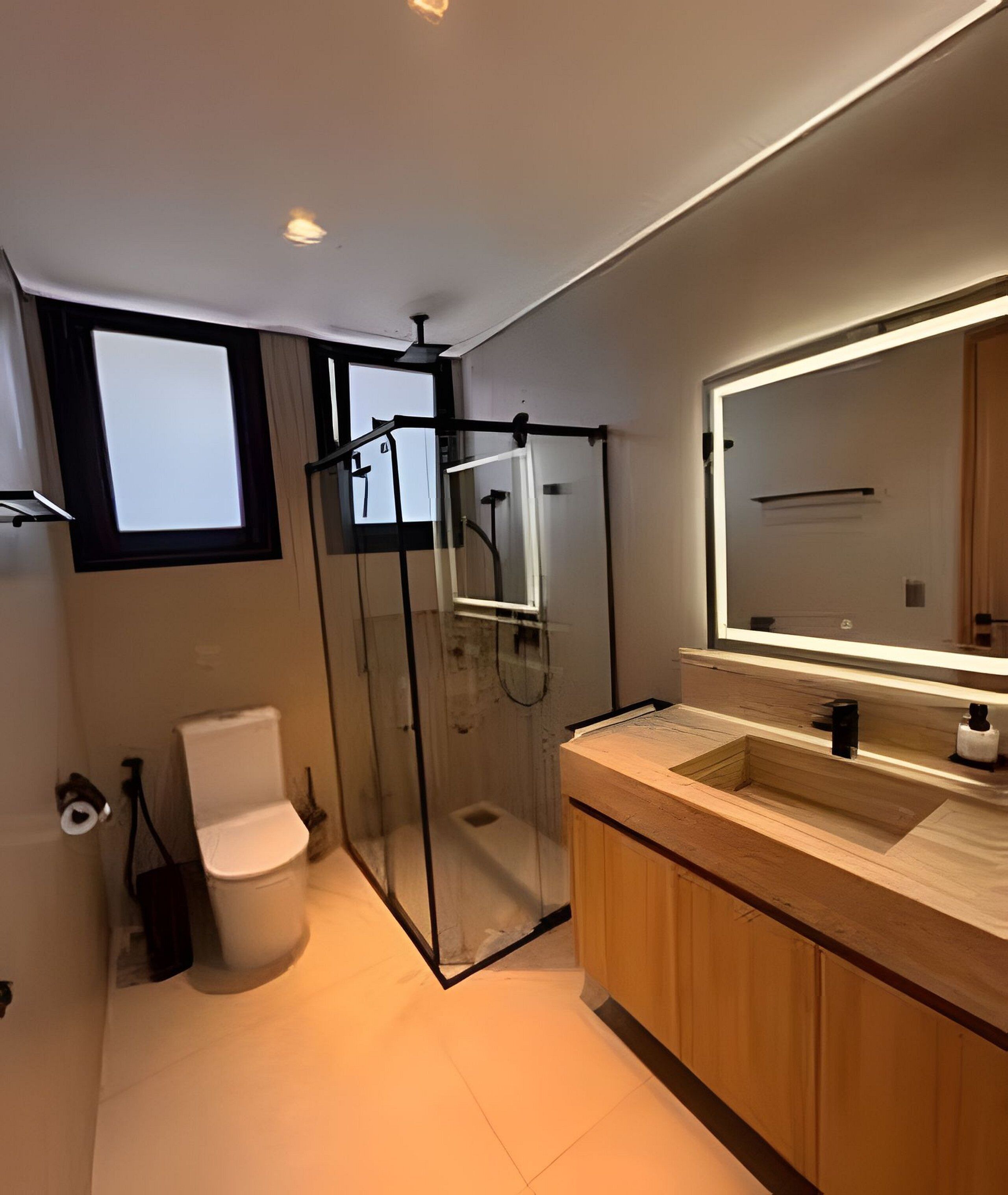 A modern bathroom with a glass shower enclosure, a toilet, and a wooden vanity with a mirror.