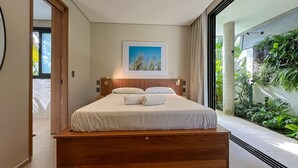 A modern bedroom with a large bed, a framed picture above the bed, and a view of greenery outside. - Vila Manga Rosa (Tibau do Sul)