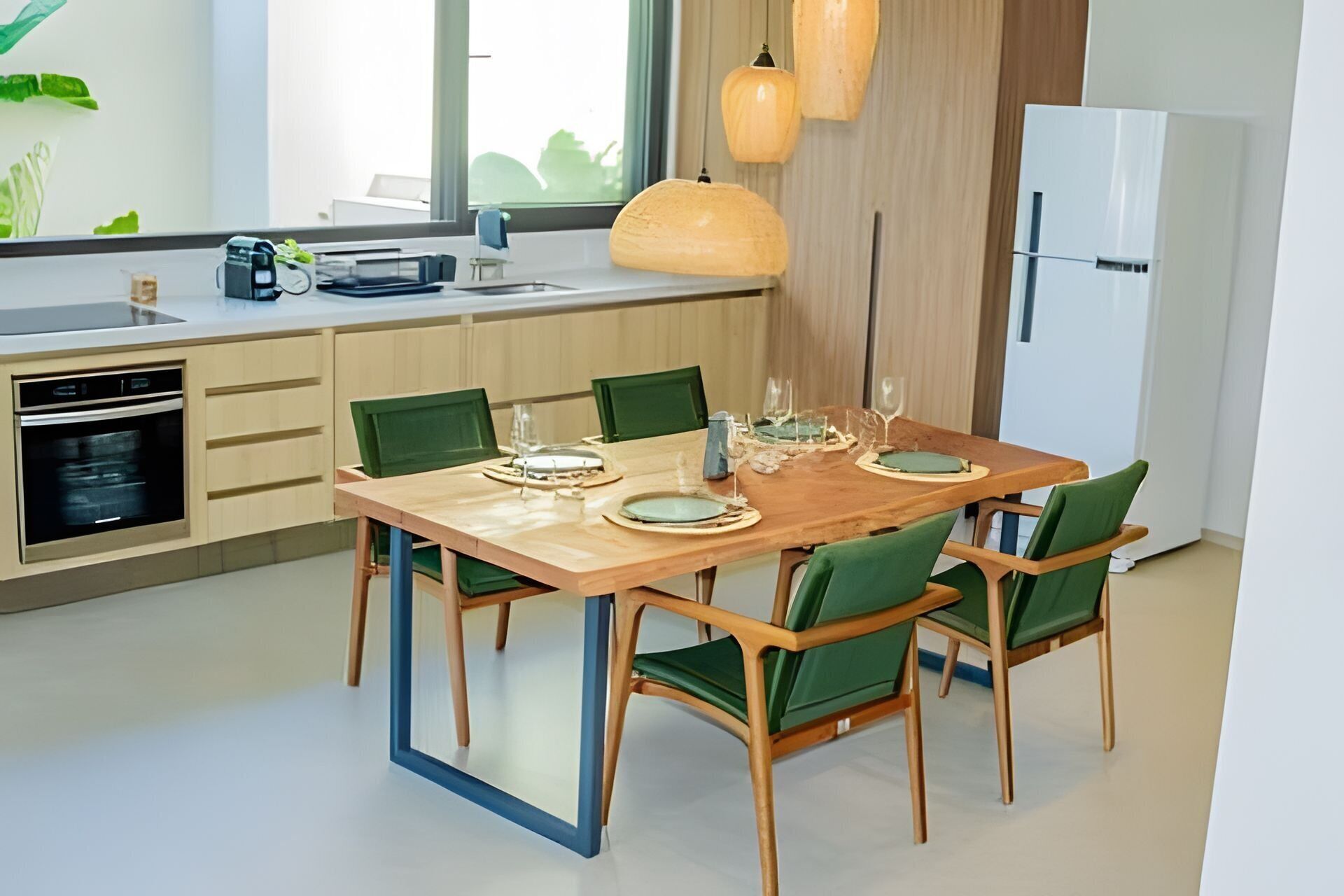 Una cocina moderna con una mesa de madera y sillas verdes, horno empotrado y lámparas colgantes.