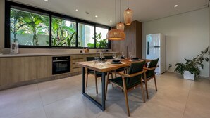 A modern kitchen with a dining area, large windows, and a refrigerator. - Vila Manga Rosa (Tibau do Sul)