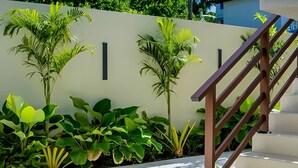A staircase with a wooden handrail leading to a white wall with vertical black stripes. - Vila Manga Rosa (Tibau do Sul)