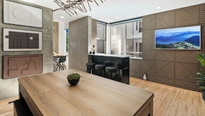 A modern kitchen with a large island, bar stools, and a TV mounted on the wall. - Walk to Gaslamp & Petco • Rooftop Spa & Game Room (San Diego)