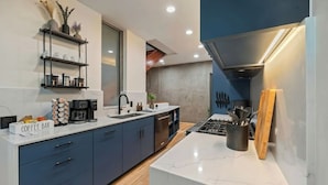 A modern kitchen with a coffee bar, built-in shelves, and a stove. - Walk to Gaslamp & Petco • Rooftop Spa & Game Room (San Diego)