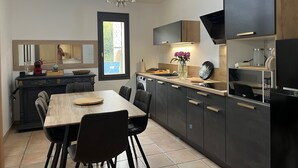 Eine moderne Küche mit dunklen Schränken, einem Holztisch und einer Chandelieber.