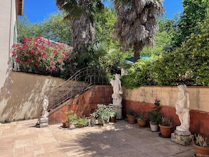 Ein Innenhof mit Steintreppe, Blumentöpfen und Statuen.