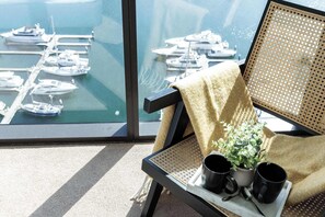A balcony with a view of a marina, a chair with a plant, and two black mugs on a tray. - Harbour View 2BR Docklands Apt Near Marvel Stadium (Docklands)