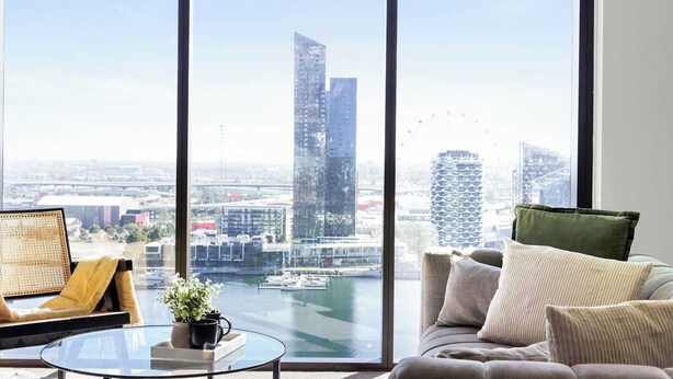 Ein modernes Wohnzimmer mit großem Fenster, einer Couch, einem Couchtisch und Blick auf Stadt und Hafen.