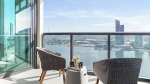 Ein Balkon mit Korbstühlen, einem kleinen Tisch und Blick auf Stadt und Wasser.