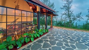A building with a tiled roof, a glass wall, and a stone-paved entrance.